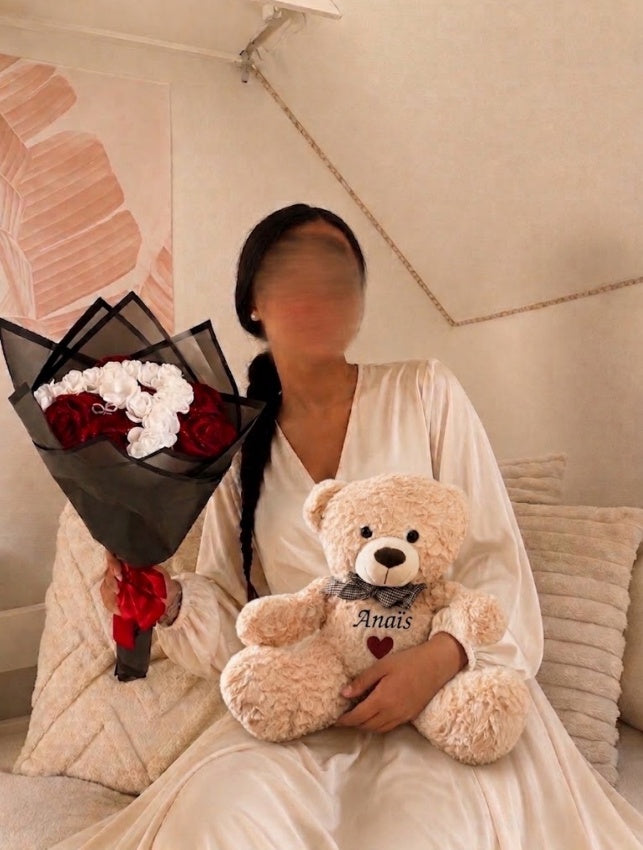 Cliente tenant un bouquet de roses éternelles et sa peluche personnalisée